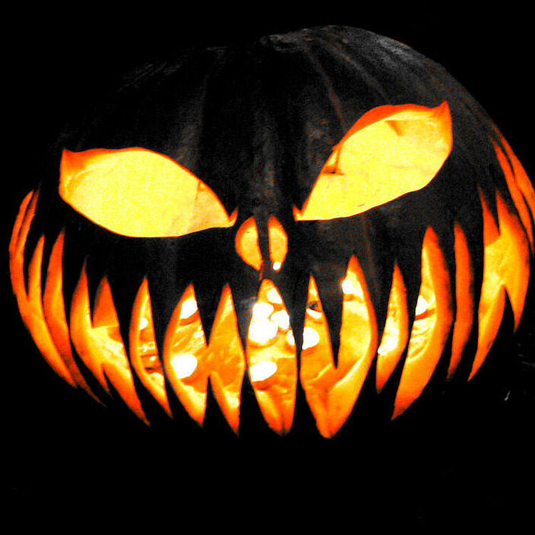 Halloween-Kürbis: Augen und Zähne leuchten vor dunklem Grund