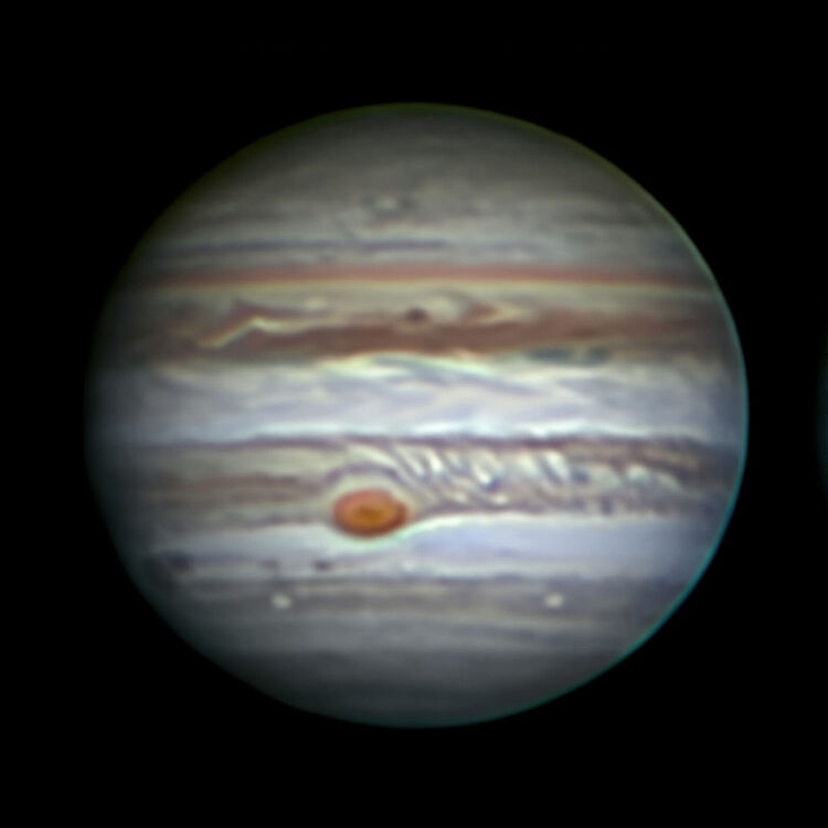 Nahaufnahme des Planeten Jupiter vor schwarzem Weltraumhintergrund, deutlich sichtbare bänderförmige Wolkenstrukturen und die markante Rote Fleck-Sturmregion auf der Südhalbkugel.