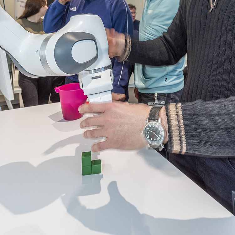 Teilnehmer der Fortbildung mit Roboterarm.
