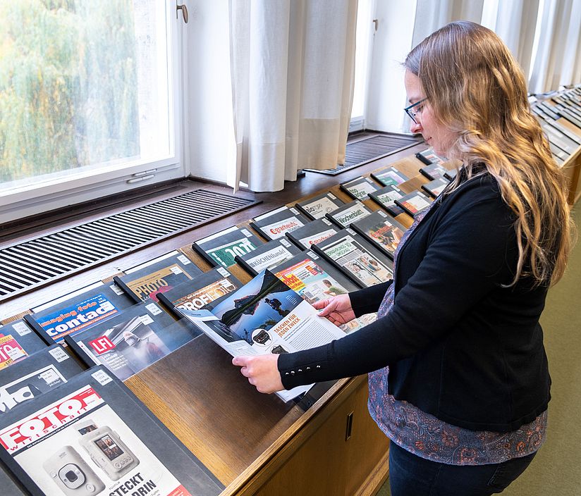 Blättern in der Zeitschriftenauslage im Lesesaal Benutzerin blättert in einer Zeitschrift im Lesesaal.