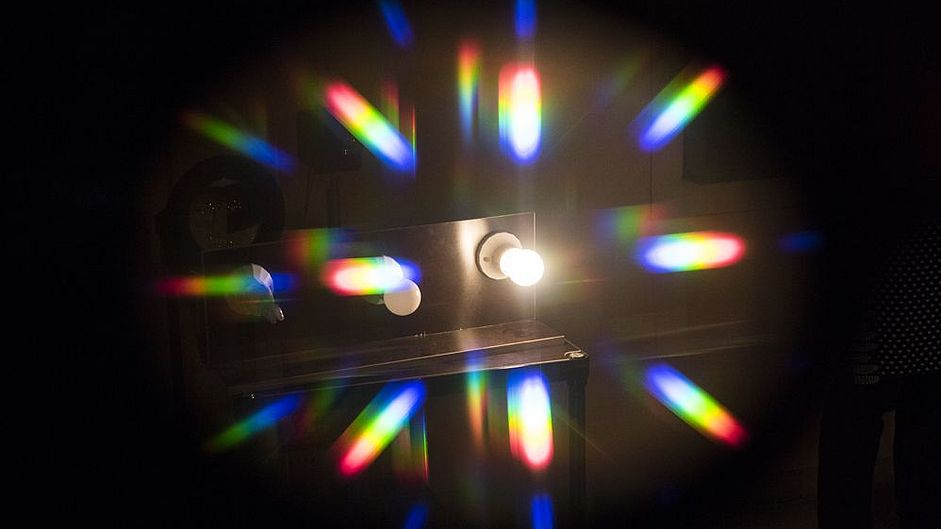Angeschaltene Glühbirne wirft Lichtstrahlen, an denen man die Fraunhofer-Linien erkennen kann.
