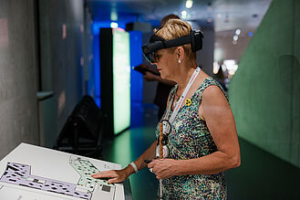 Eine blinde Frau an einem taktilen Übersichtsplan im Zukunftsmuseum.