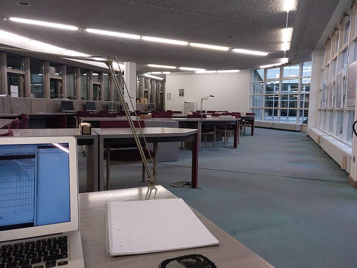 Raum des Bundesarchivs in Koblenz. Einige Reihen an Tischen und Stühlen sind zu sehen, sowie PCs für die Recherche.