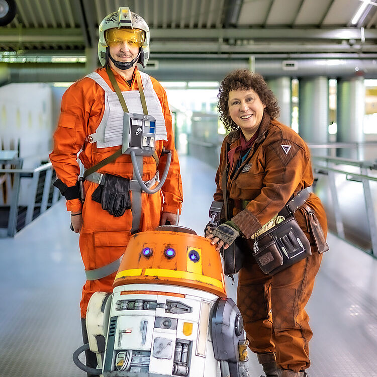 Kostümträger:innen verkleidet als Star-Wars-Charaktere XwingPilot, Chopper und Peli Motto in der Flugwerft Schleißheim