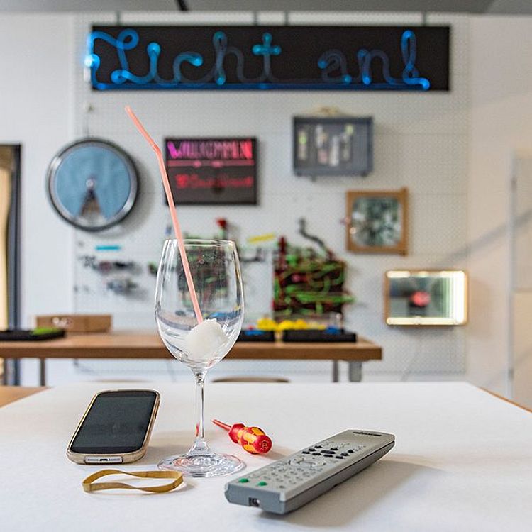 Ein Smartphone auf einem Tisch mit Weinglas und Schraubenzieher.