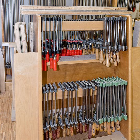 Ein Regal mit Schraubzwingen und Leisten in der Schreinerei.