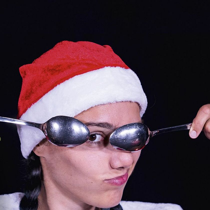 Eine Frau im Weihnachtsmannkostüm hält sich zwei Löffel vor die Augen.