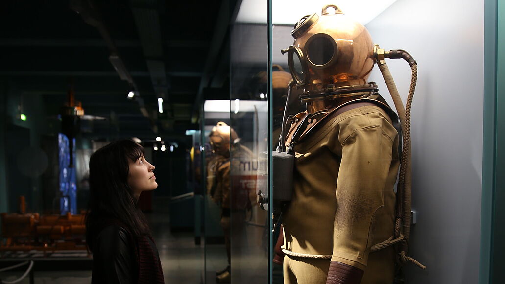 Frau betrachtet ein Tauchgerät mit freier Helmatmung.