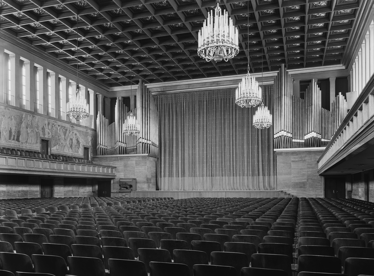Schwarzweiß Fotografie Kongresssaal mit Leuchtern und Bühne