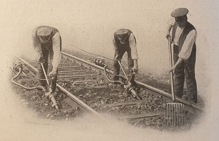 Railway workers reinforcing ballast underneath the tracks.