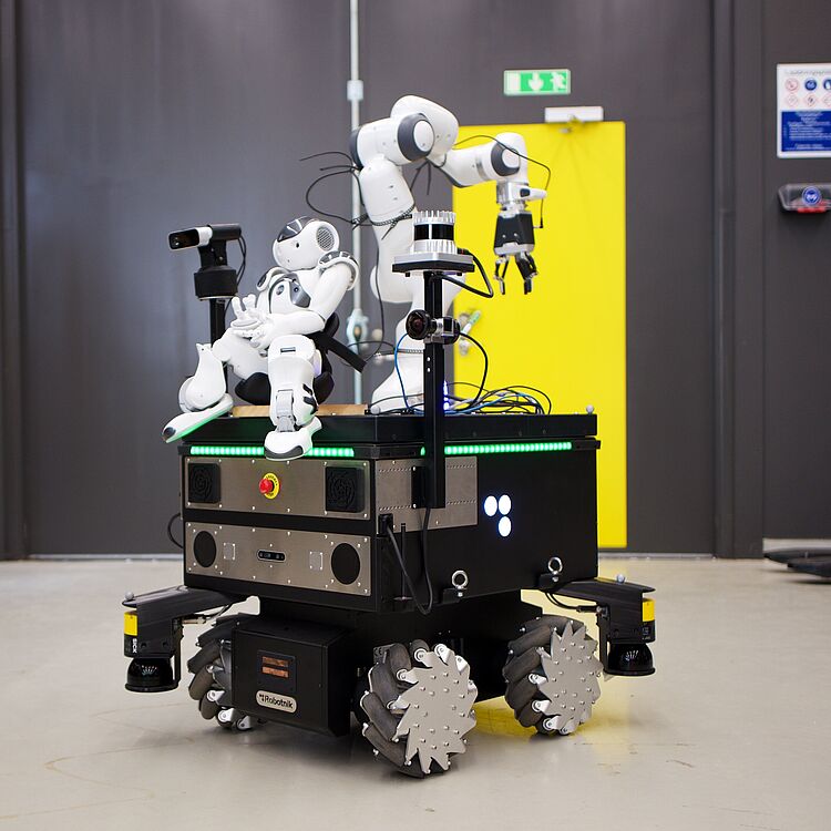Roboter Nao sitzt auf Roboter DARKO.