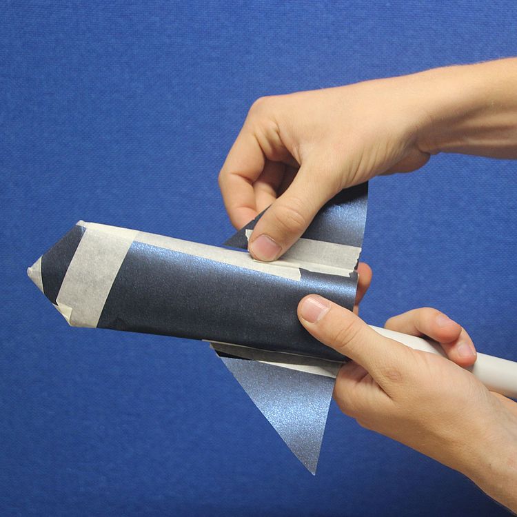 Hände arbeiten an einem Papierflieger