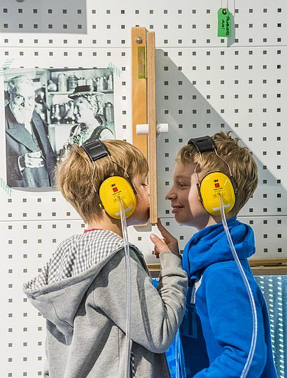Zwei Jungen mit Gehörschutz experimentieren.