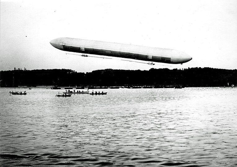 Schwarz-weiß Foto zeigt das erste Zeppelin-Luftschiff über der Manzeller Bucht.