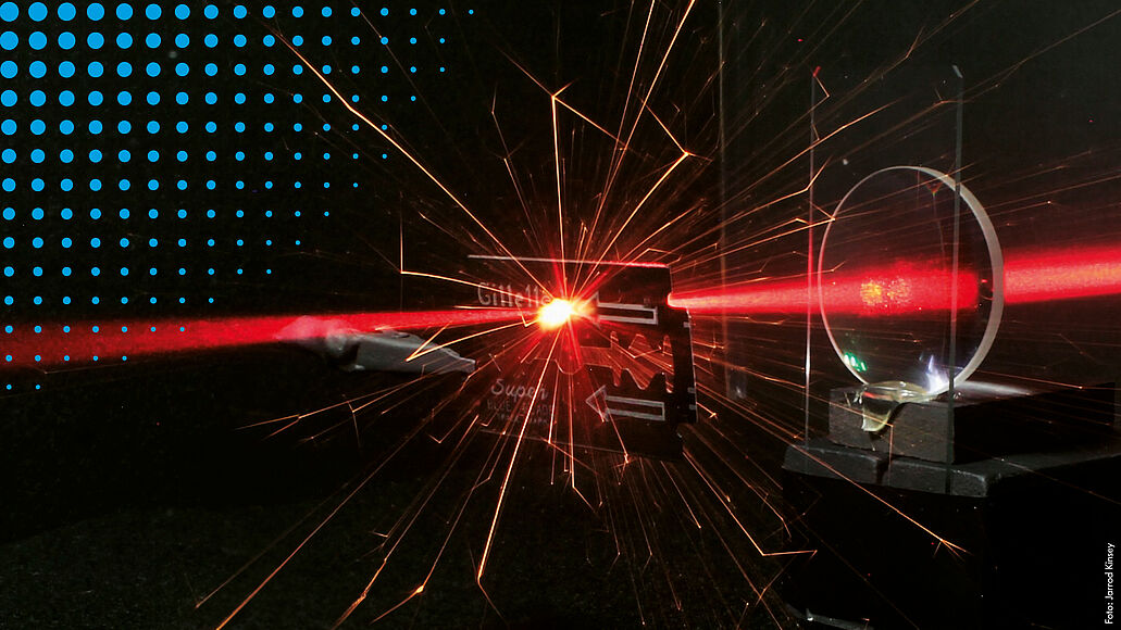 Laser trifft auf Rasierklinge und erzeugt Lichtfunken.