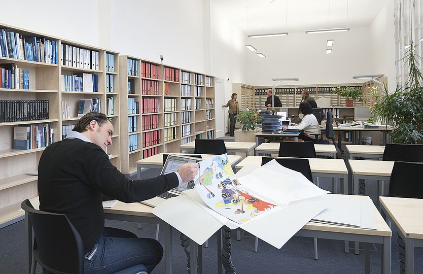 Ein Mann arbeitet mit Dokumenten an einem Tisch im Lesesaal des Archivs.