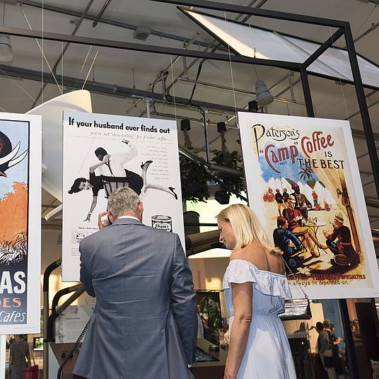 Besucherin und Besucher betrachten Kaffee Werbeplakate.