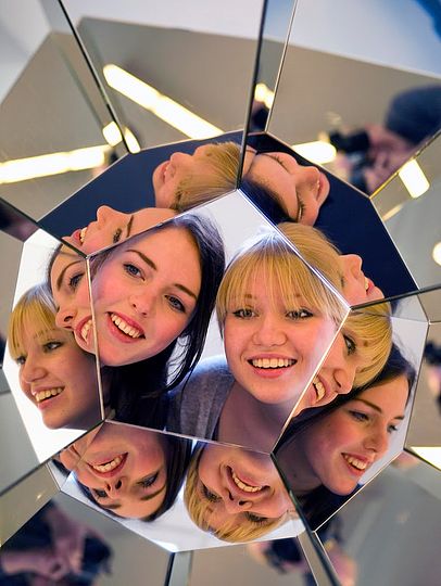 Zwei junge Frauen blicken in ein großes Kaleidoskop.