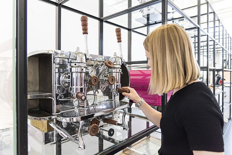 Junge Frau betrachtet das Kaffeemaschinenregal.