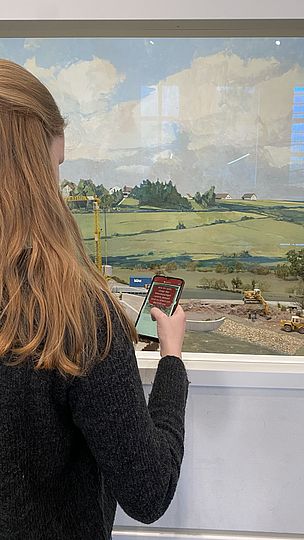 Jugendliche steht mit ihrem Smartphone vor einem Diorama der Ausstellung Landwirtschaft- und Ernährung.