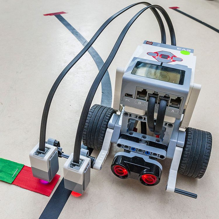 Lego-Roboter überprüft Papier-Ampel am Boden.