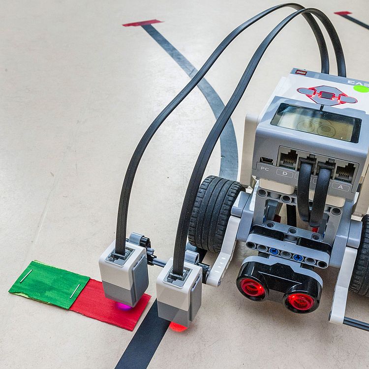 Lego-Roboter überprüft Papier-Ampel am Boden.