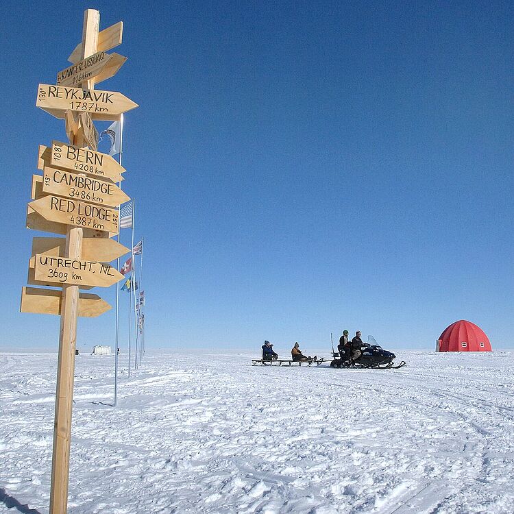Schneelandschaft mit hölzernem Hinweisschild in verschiedene Richtungen