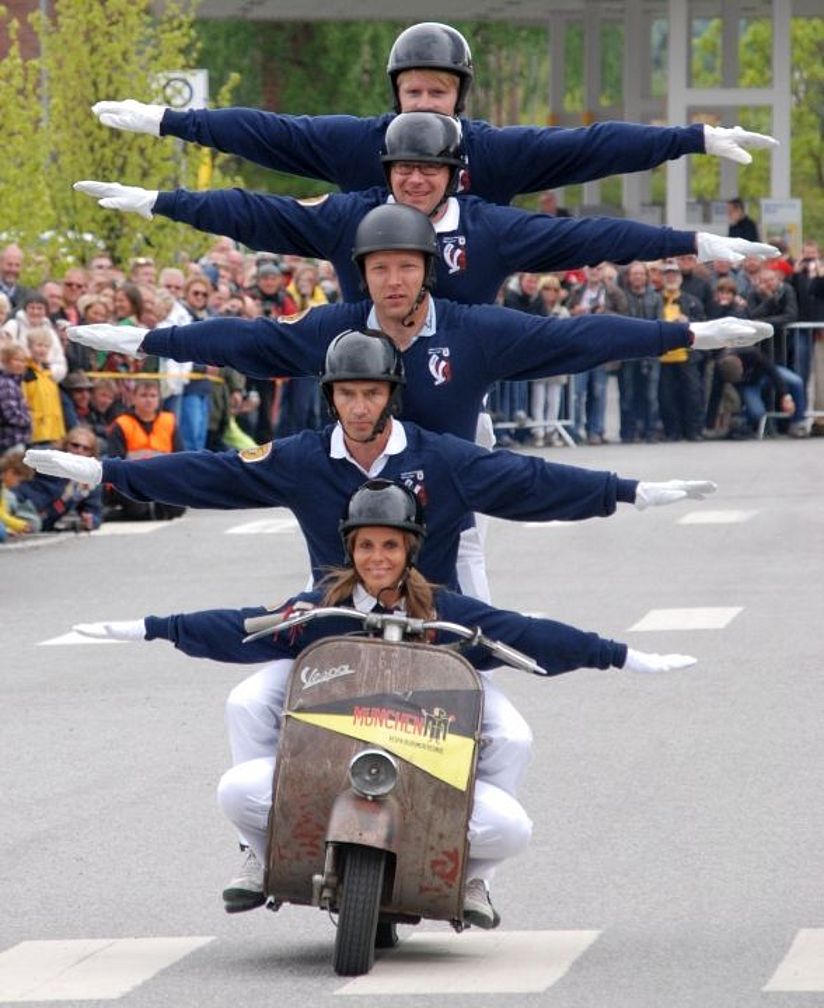 fünf Fahrer sitzen übereinander auf einer fahrenden Vespa
