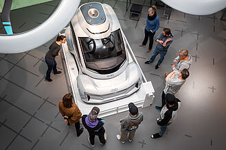 Eine Gruppe von Menschen steht bei einer Tour durchs Museum vor einem Exponat.