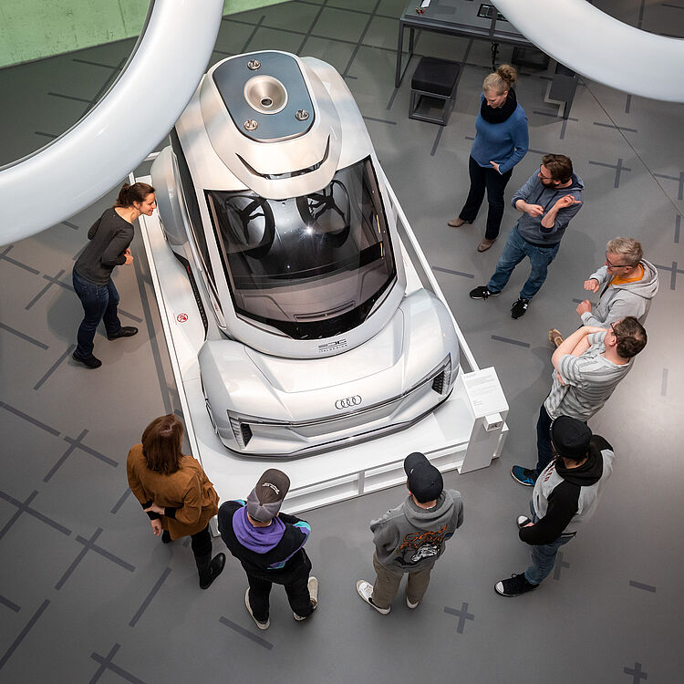 Eine Gruppe von Menschen steht bei einer Tour durchs Museum vor einem Exponat.