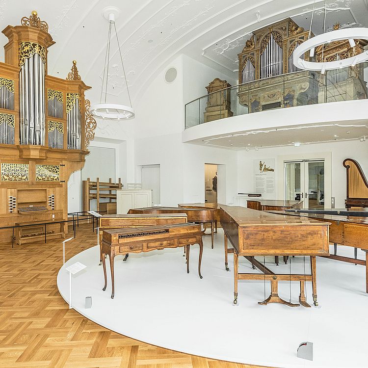 Blick in den ersten Raum der Ausstellung Musikinstrumente mit zwei großen Orgeln und weiteren Tasteninstrumenten.