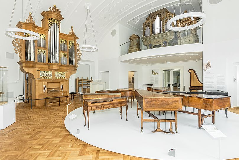 Blick in den ersten Raum der Ausstellung Musikinstrumente mit zwei großen Orgeln und weiteren Tasteninstrumenten.