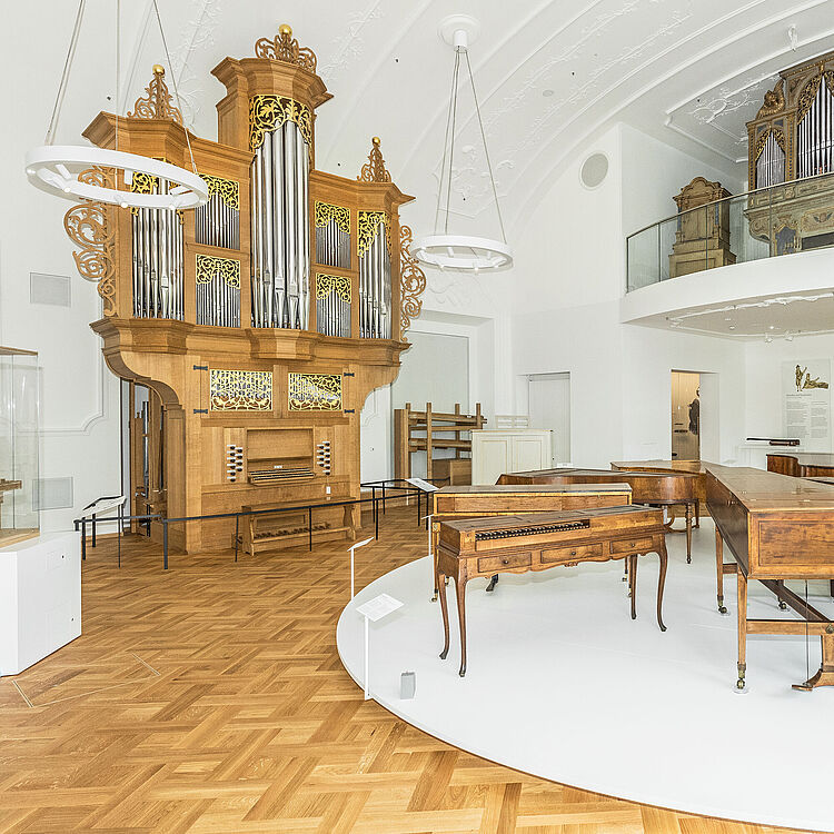 Blick in den ersten Raum der Ausstellung Musikinstrumente mit zwei großen Orgeln und weiteren Tasteninstrumenten.