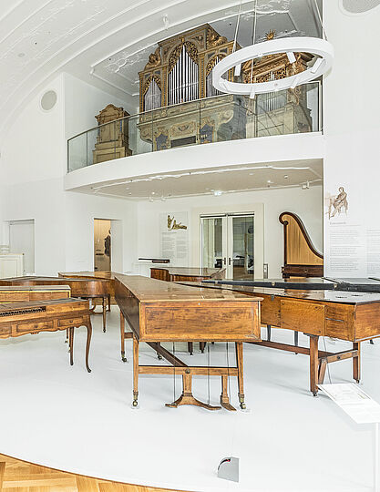 Blick in den ersten Raum der Ausstellung Musikinstrumente mit zwei großen Orgeln und weiteren Tasteninstrumenten.