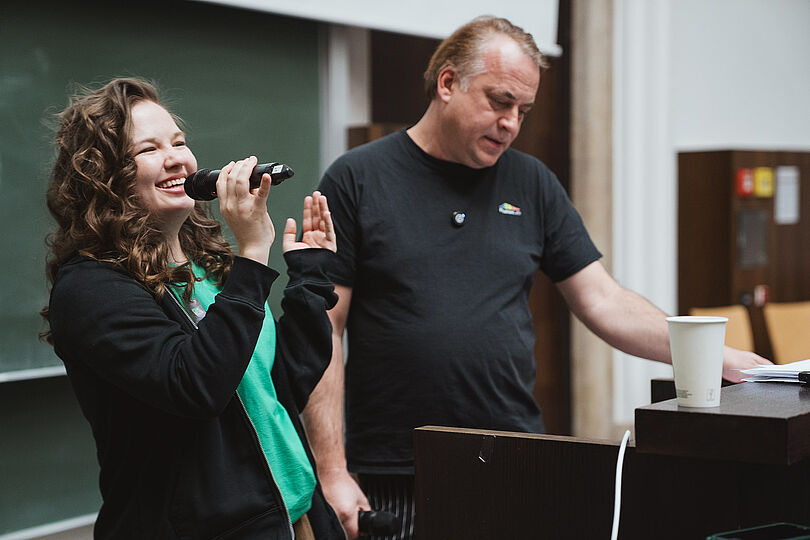 zwei Menschen, eine Frau mit Mikrophon