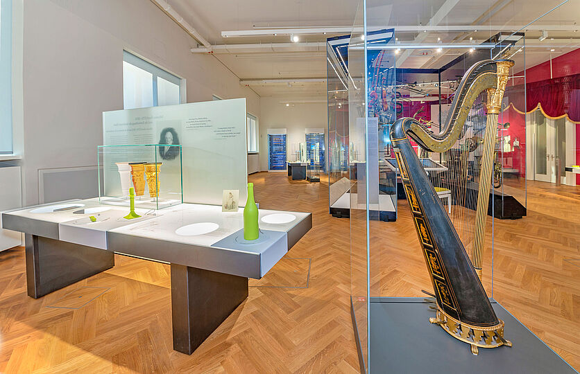 Die Doppelpedalharfe in der Ausstellung Musikinstrumente mit Blick auf den Orchesterkubus.