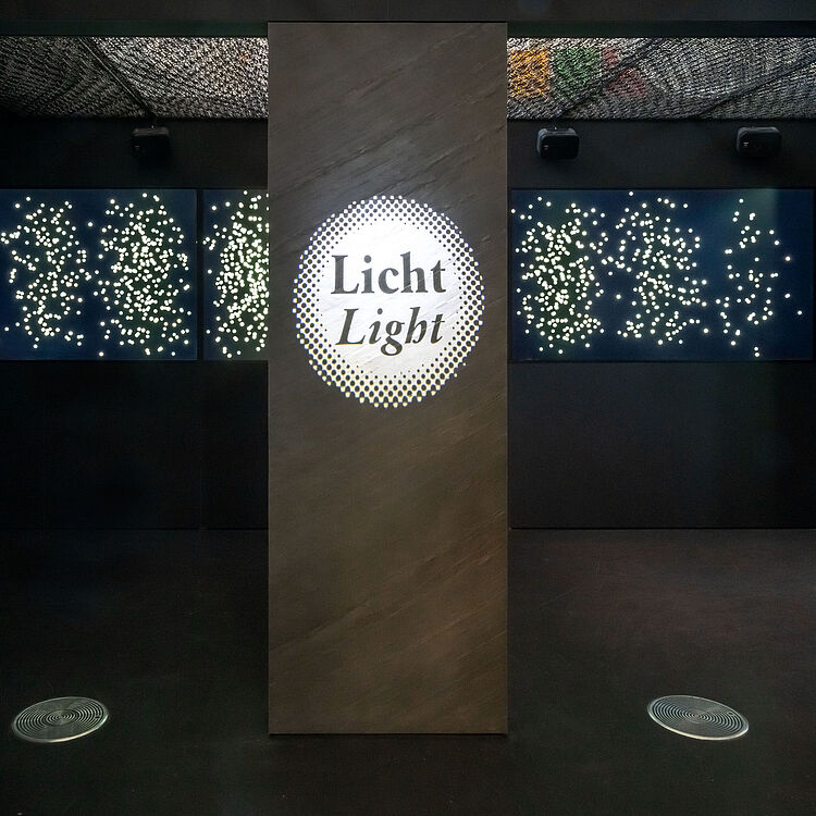 Lichtprojektionen auf dunkler Wand zeigen viele kleine weiße Punkte.