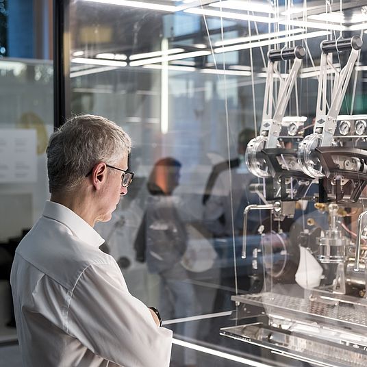Besucher betrachtet Kaffeemaschine in einerr Vitrine.