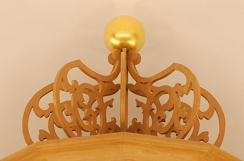 Foto der Krone auf dem Mittelturm der Ahrend-Orgel aus durchbrochenen Holzornamenten, auf denen eine goldene Kugel thront
