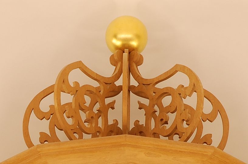 Krone auf dem Mittelturm der Ahrend-Orgel aus durchbrochenen Holzornamenten, auf der eine goldene Kugel thront.