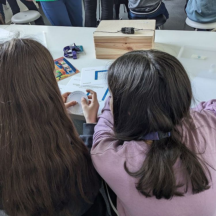 Kinder beim Versuch, ein Zahlenschloss mit einer Transkriptions-Scheibe zu öffnen.