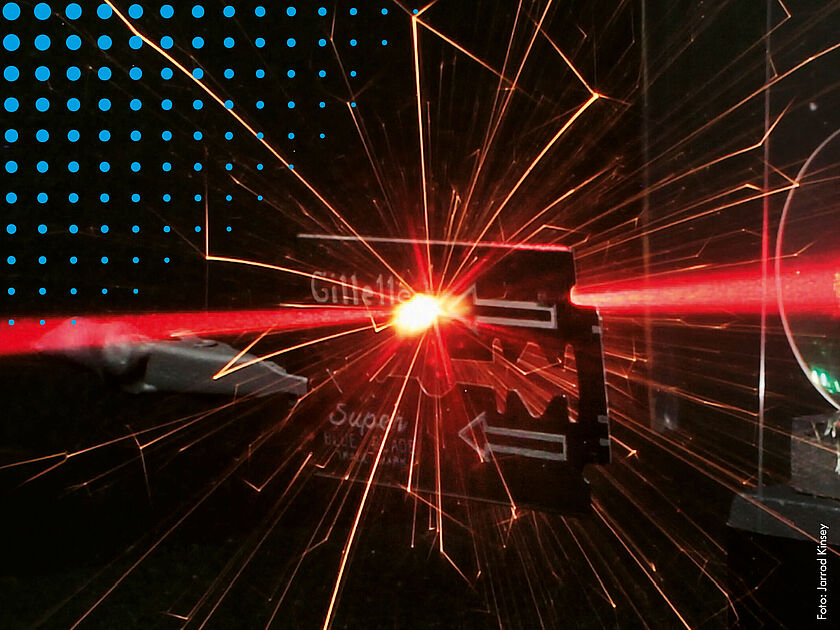 Laser trifft auf Rasierklinge und erzeugt Lichtfunken.