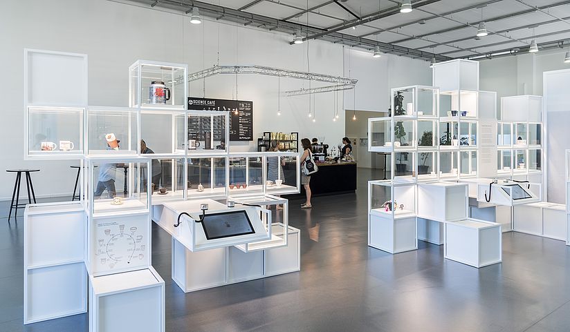 Tassenregal und Science Café.