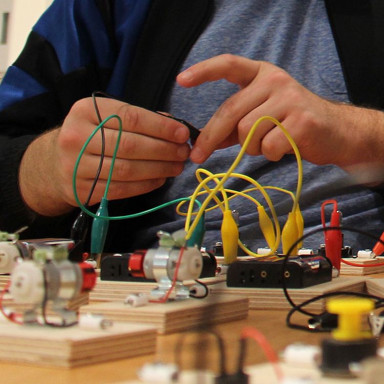 Zwei junge Erwachsene bauen mit unterschiedlichen Elementen Stromkreise zusammen.