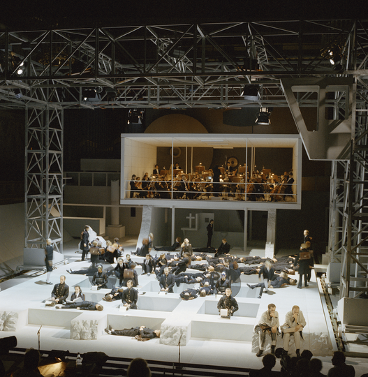 Fotografie einer Theaterkulisse im Kongresssaal mit Schauspielenden auf und über der Bühne.