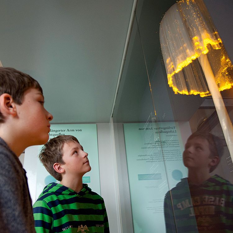 Jungen betrachten Glasfaser-Exponat mit Licht