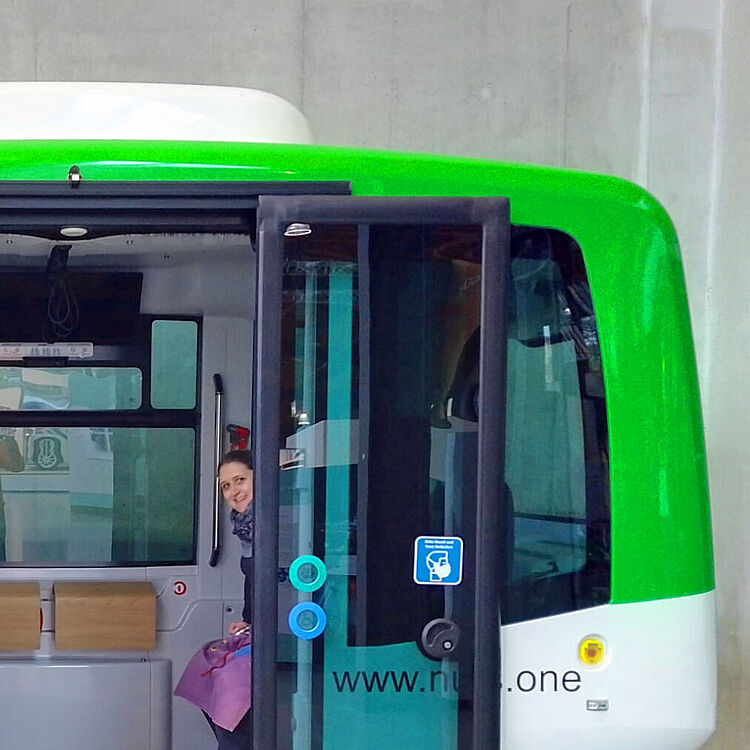 eine Frau schaut aus einem fahrerlosen Bus, Ausstellungsstück autonomes öffentliches Verkehrsmitteln. 