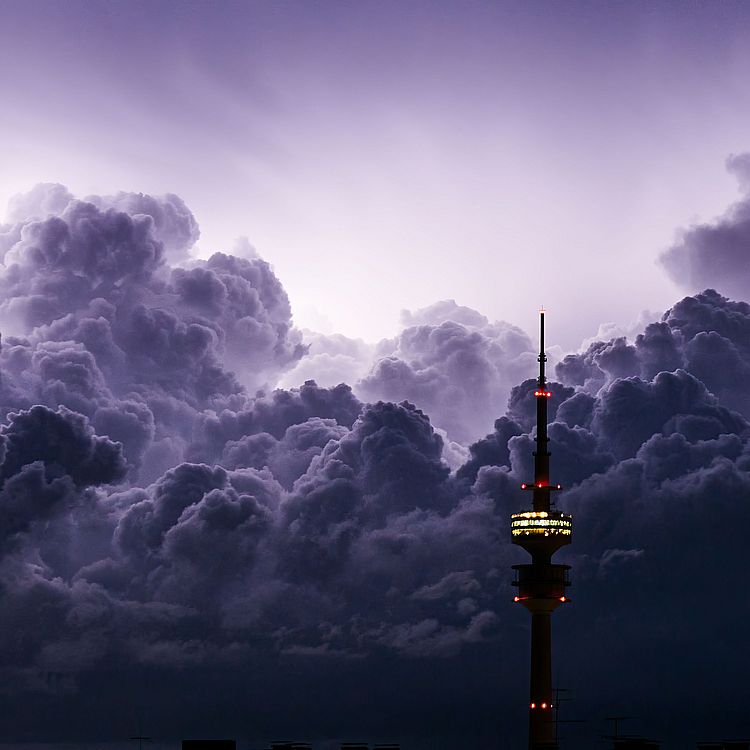 Schwarze Gewitterwolken und davor ist ein Fernsehturm zu sehen.
