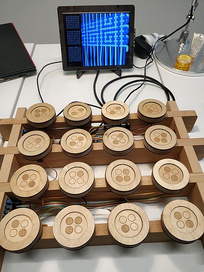 Pattern-matrix for 8x8 repeats, developed by FoAM Kernow. The light and dark circles on the tokens indicate points where to lift warp-threads. Applied to alternating white and blue threads, the result is a meander pattern