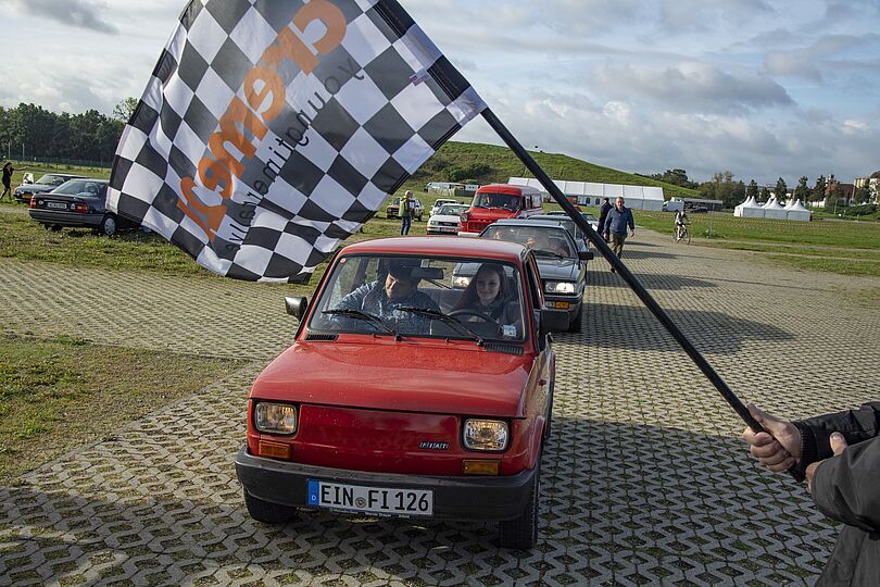 Creme21 Youngtimer Rallye. Autos beim Start mit Startflagge.